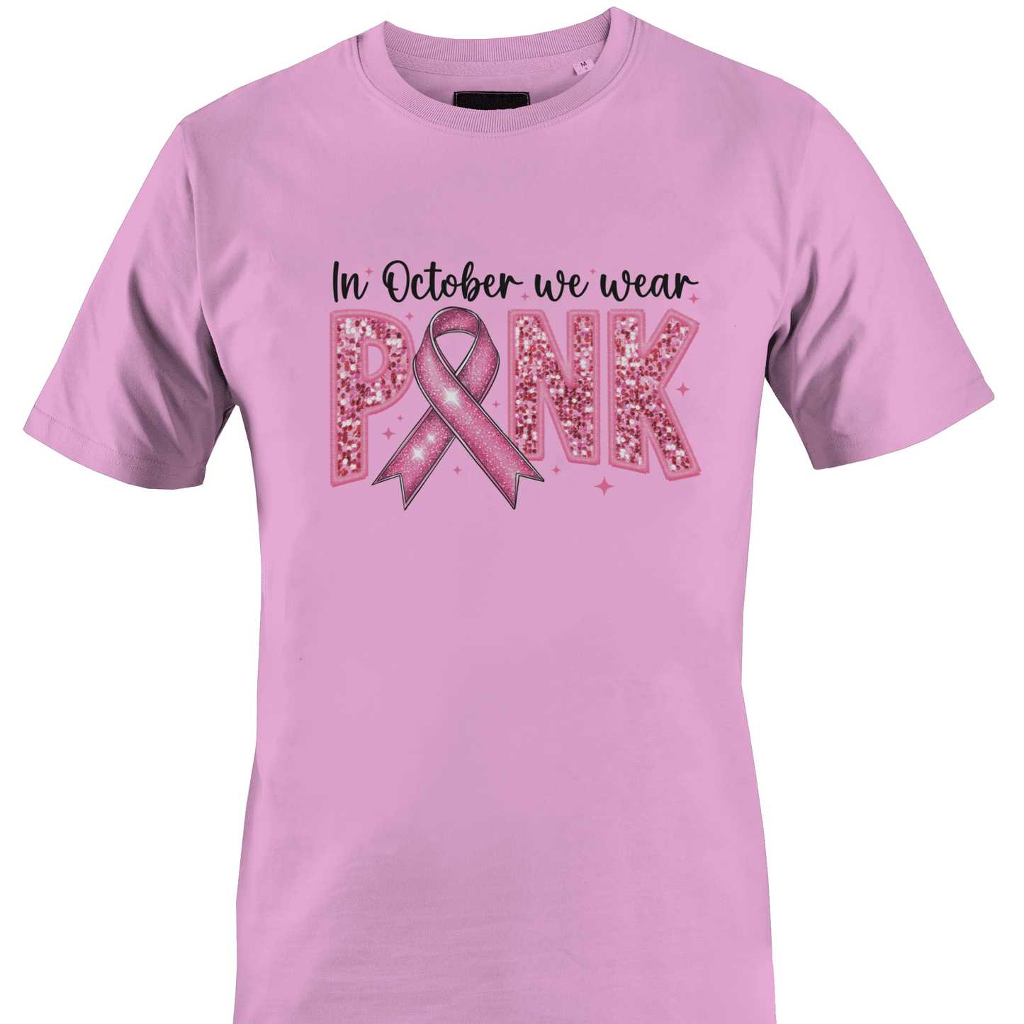 A pink short-sleeve crewneck t-shirt featuring a pink graphic on the front that reads 'In October we wear PINK' with a pink ribbon and glitter-textured letters by Monkey's Creations.