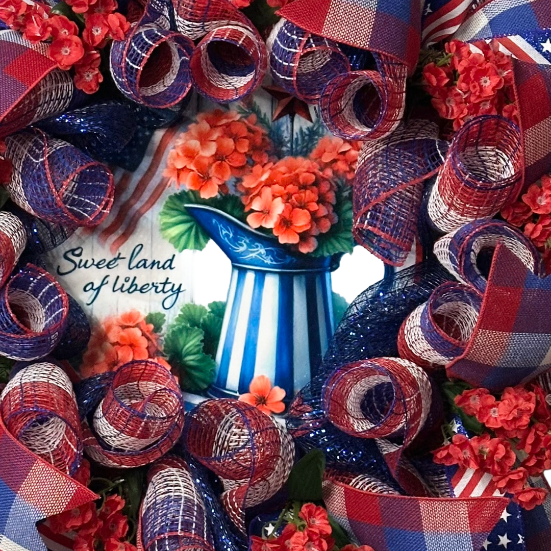 Deco mesh and ribbon wreath with red, white, and blue ribbons and flowers, featuring a 'Sweet Land of Liberty' by Monkey's Creations.