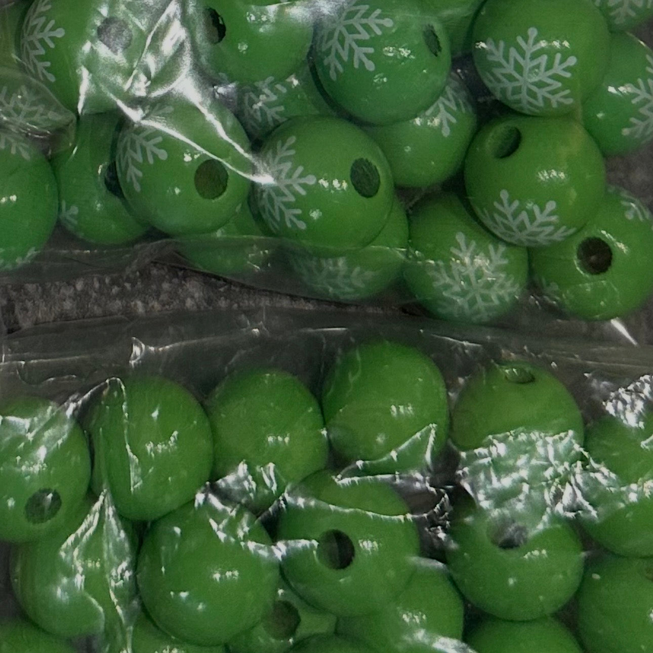 close up of green wooden beads with a snowflake