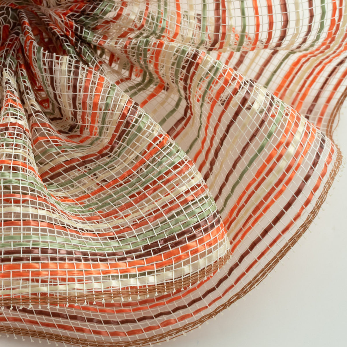 Close up of orange, sage green, brown, cream and tan vertical wide stripe striation deco mesh weave carried by Monkey's Creations. MPN - RE1369YE.