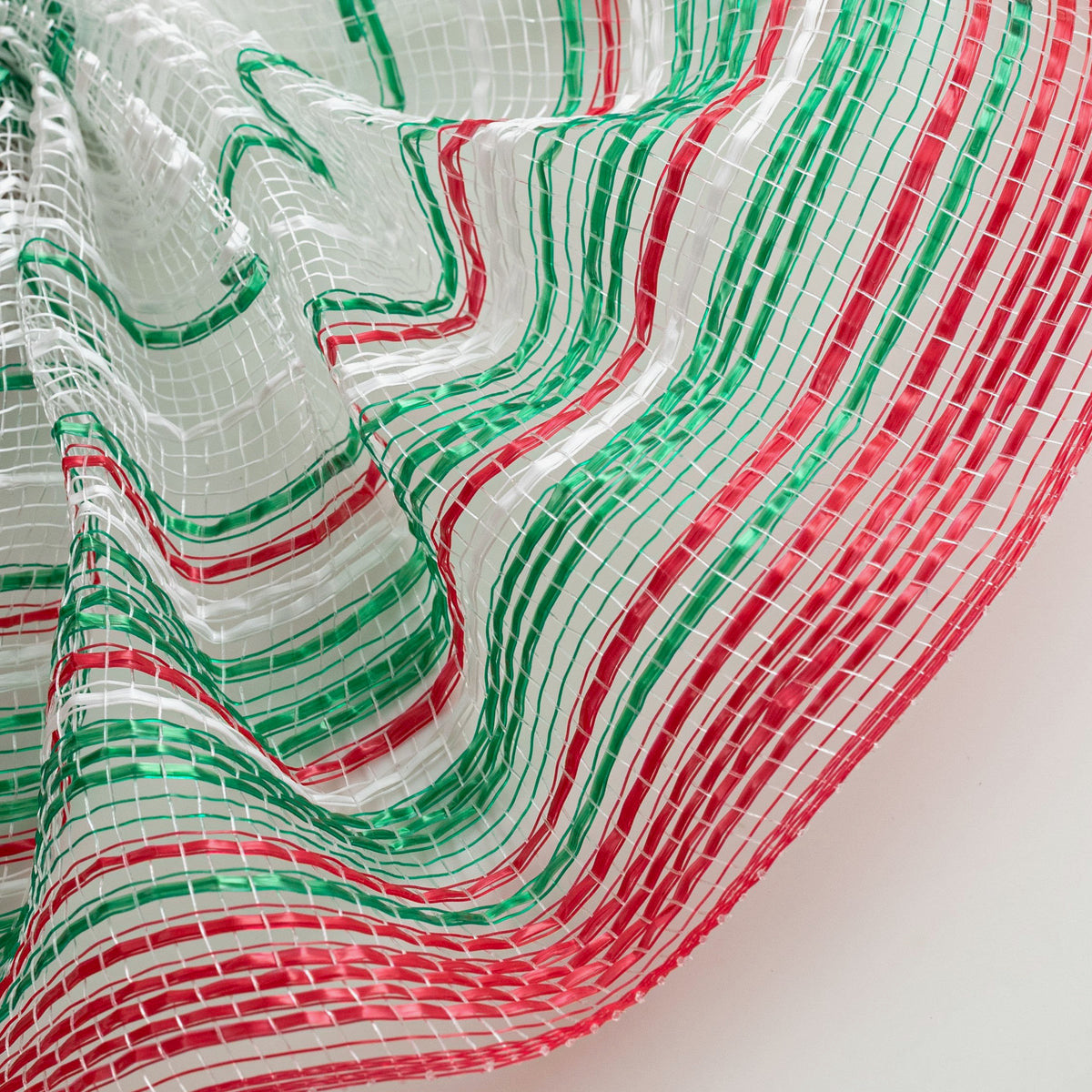 Close up of ombre style red, green and white vertical wide stripe deco mesh weave