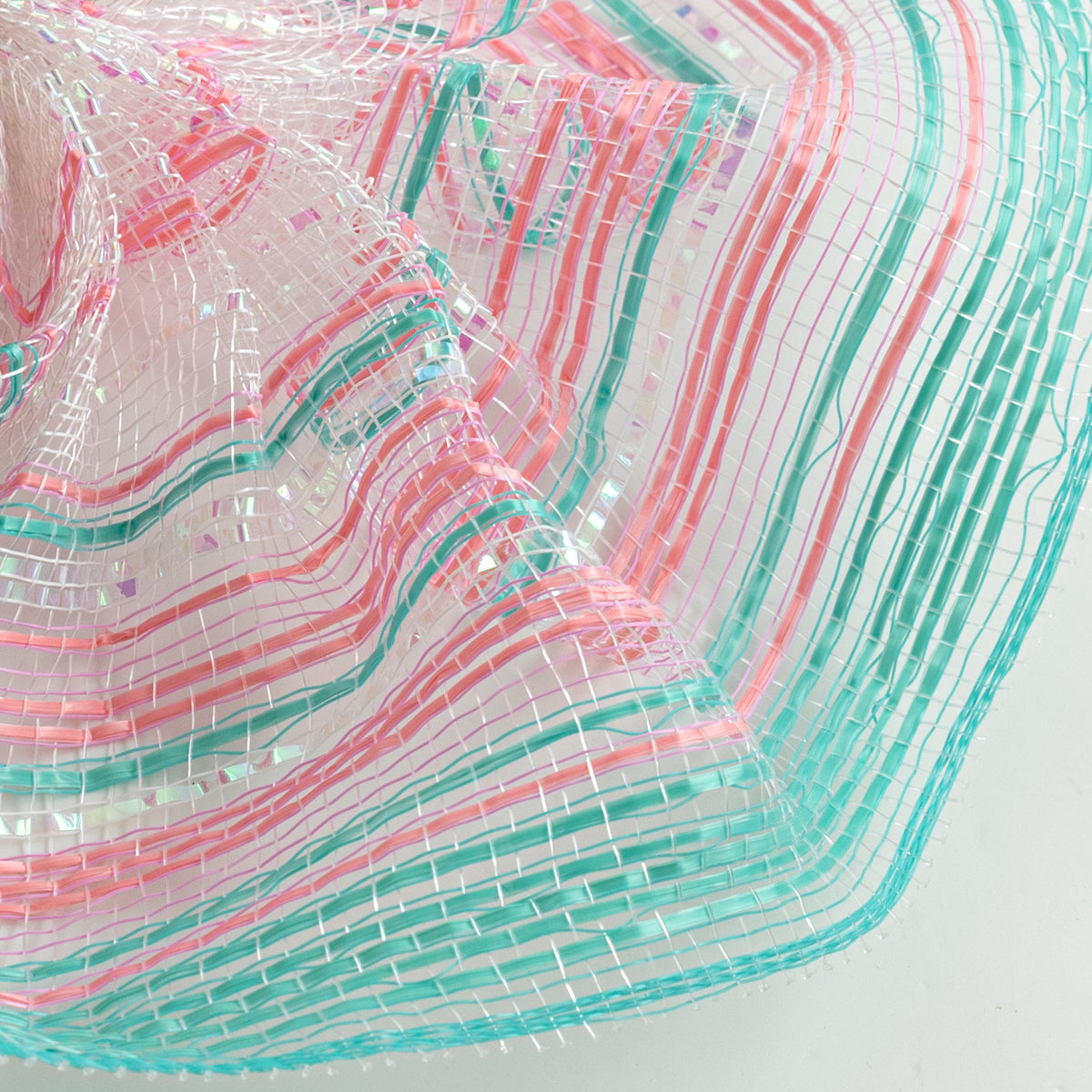 Close up of ombre style blush pink, teal and iridescent white vertical wide stripe deco mesh weave
