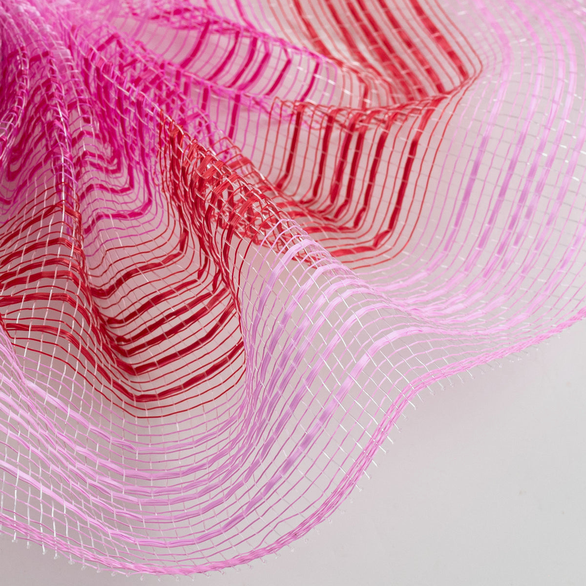 Close up of pink, hot pink and red vertical wide stripe deco mesh weave MPN RE138566