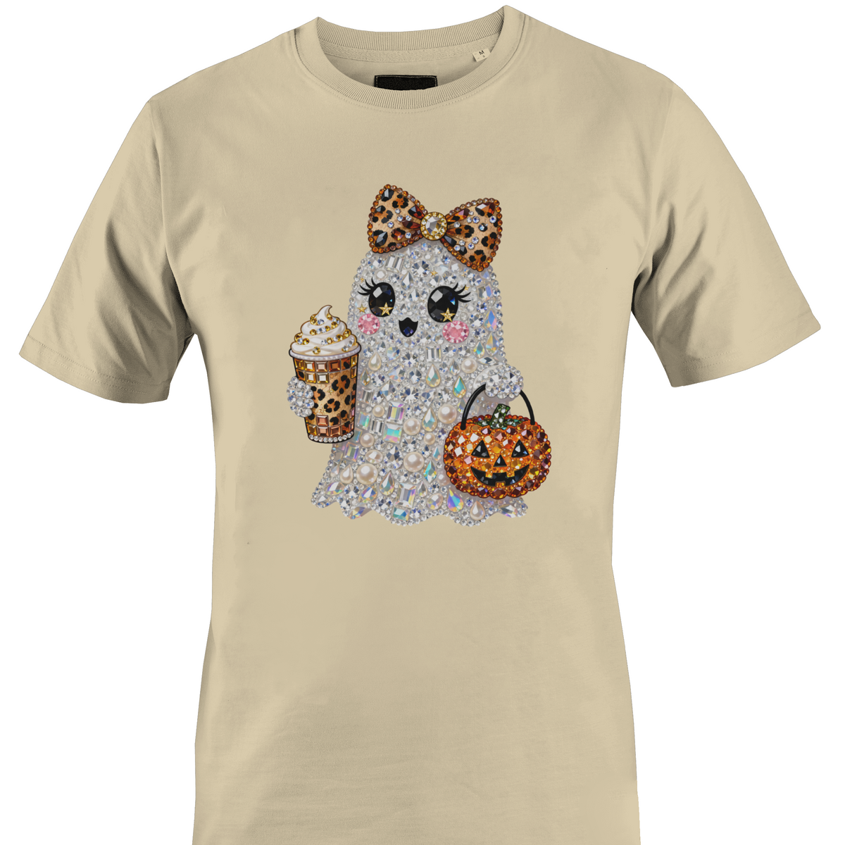 A beige short-sleeve crewneck t-shirt featuring a graphic of a cute ghost character covered in rhinestones, holding a leopard-print pumpkin bucket and a leopard-print drink by Monkey's Creations.