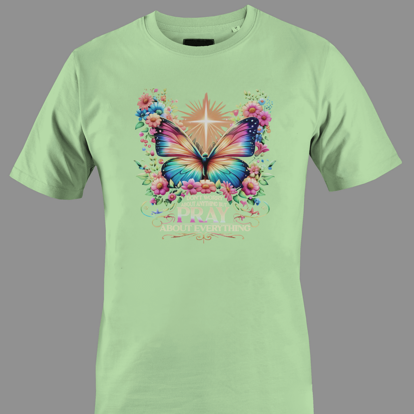 Light green t-shirt with a colorful butterfly and florals with text Pray 
