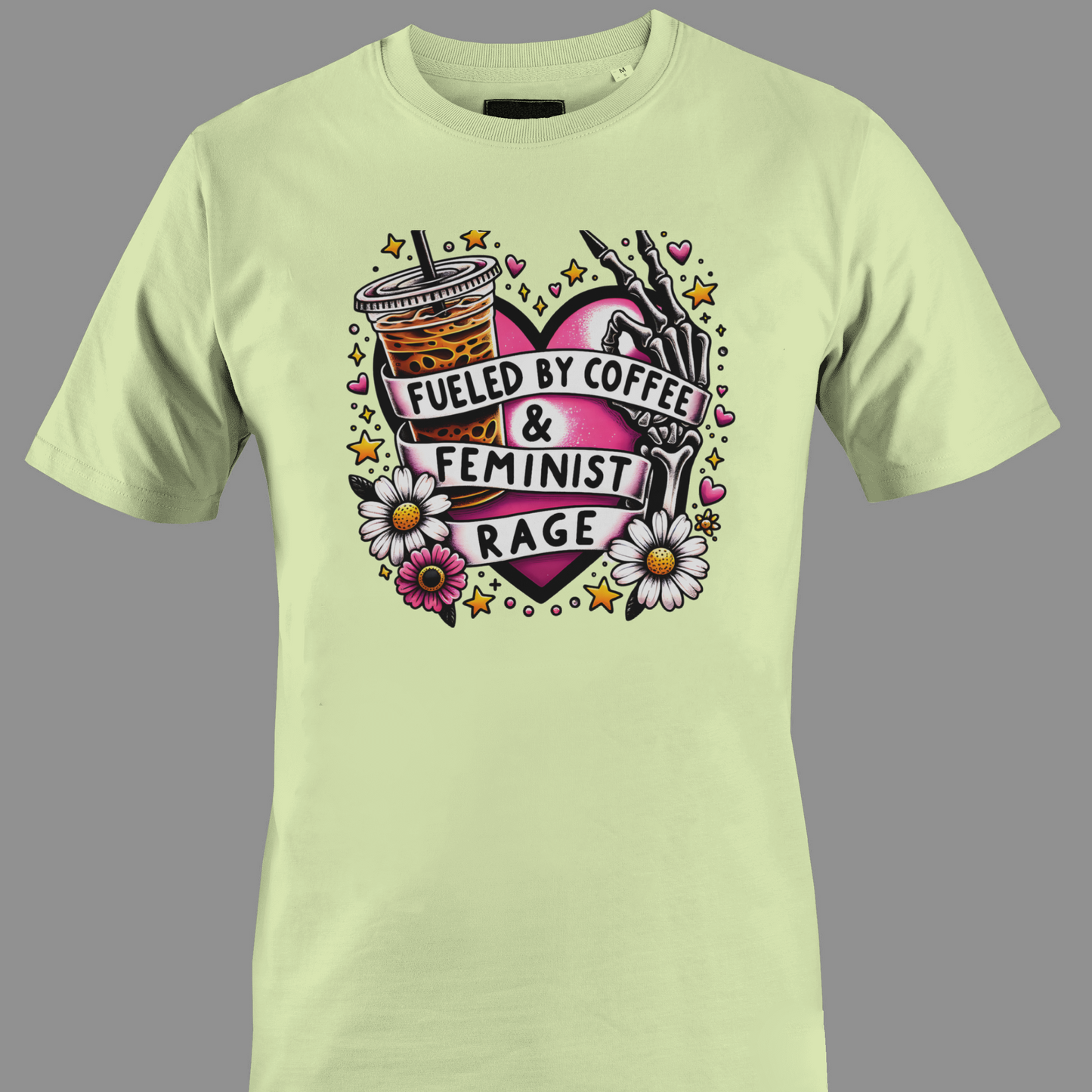 Light yellow t-shirt with Iced coffee, flowers, and a hand holding a pen, with text 'Fueled by Coffee & Feminist Rage'.