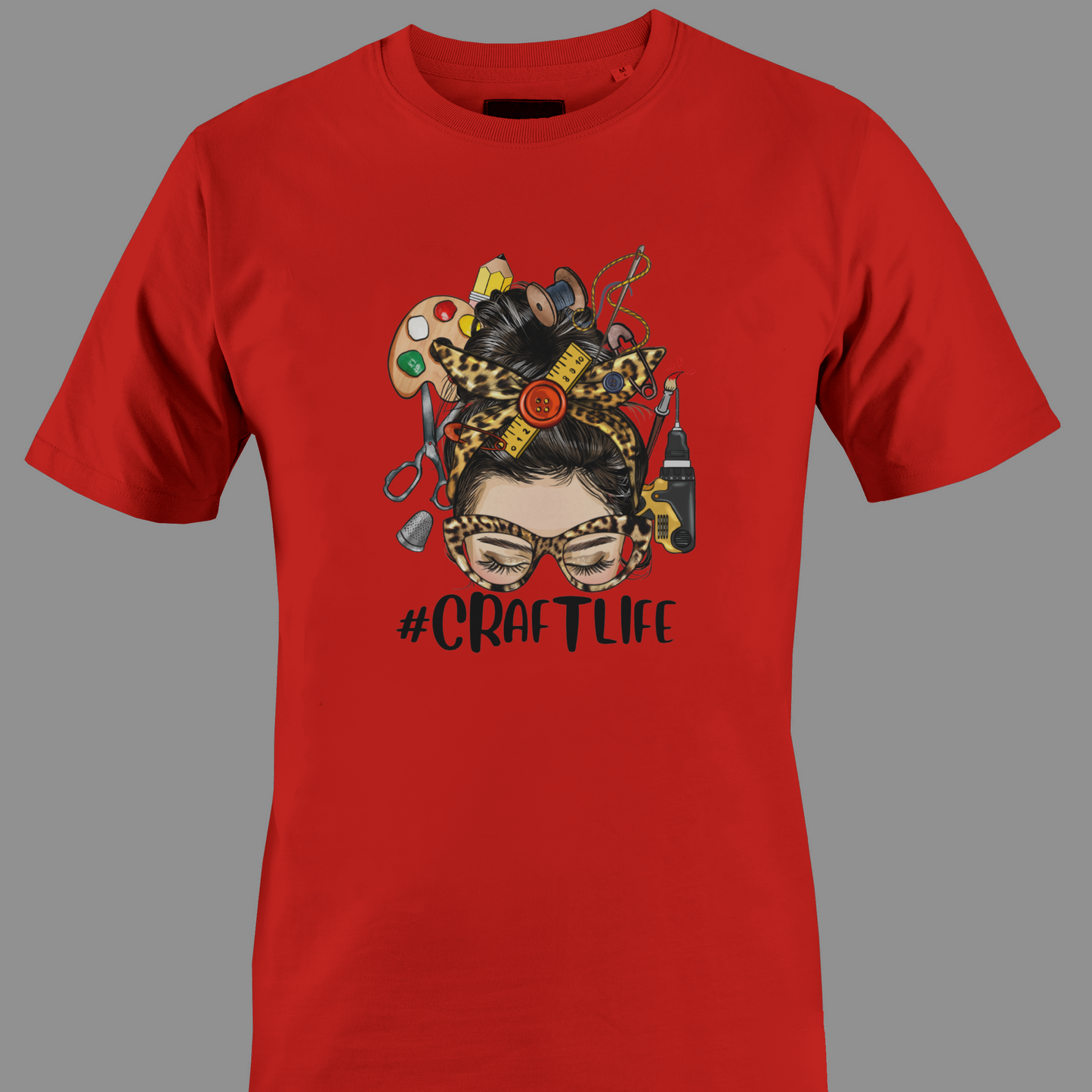Red t-shirt with a graphic design featuring a woman's face with craft supplies around her head, featuring the hashtag #CRAFTLIFE.