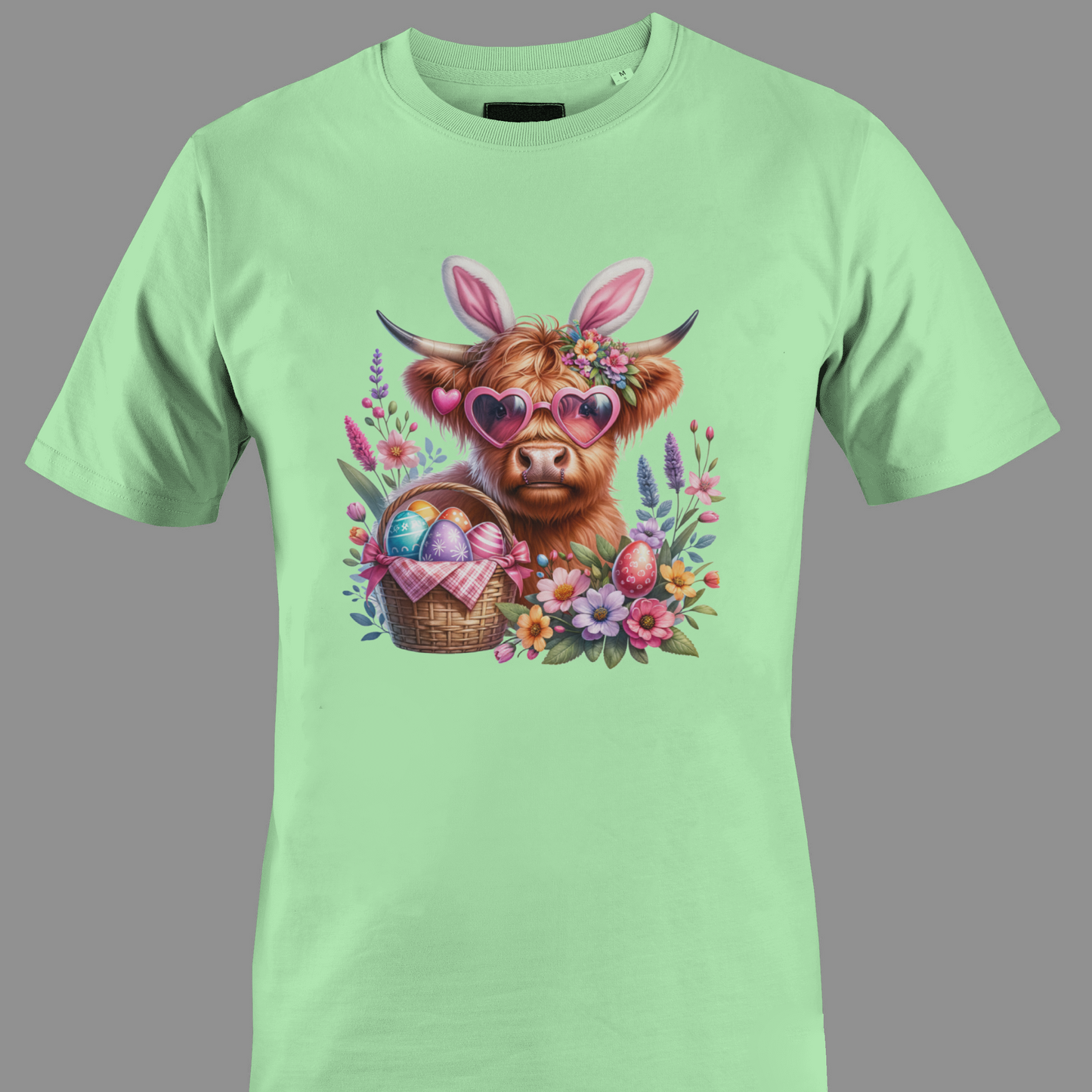 Light green t-shirt with a highland cow wearing heart glasses with an easter egg basket and flowers