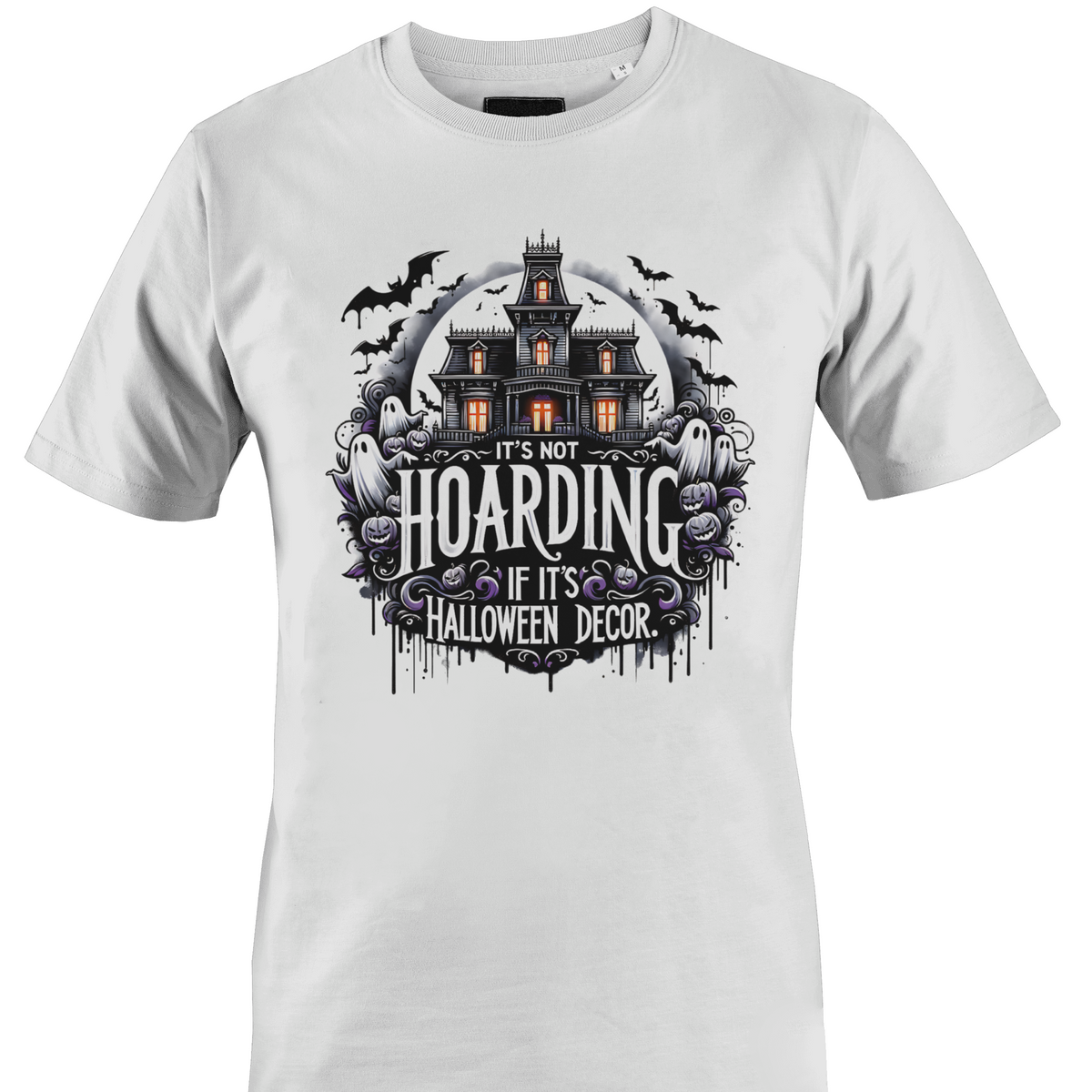 A white short-sleeve crewneck t-shirt featuring a Halloween-themed graphic print on the front. The graphic shows a haunted house, ghosts, and purple flowers with the text 'IT'S NOT HOARDING IF IT'S HALLOWEEN DECOR' by Monkey's Creations.