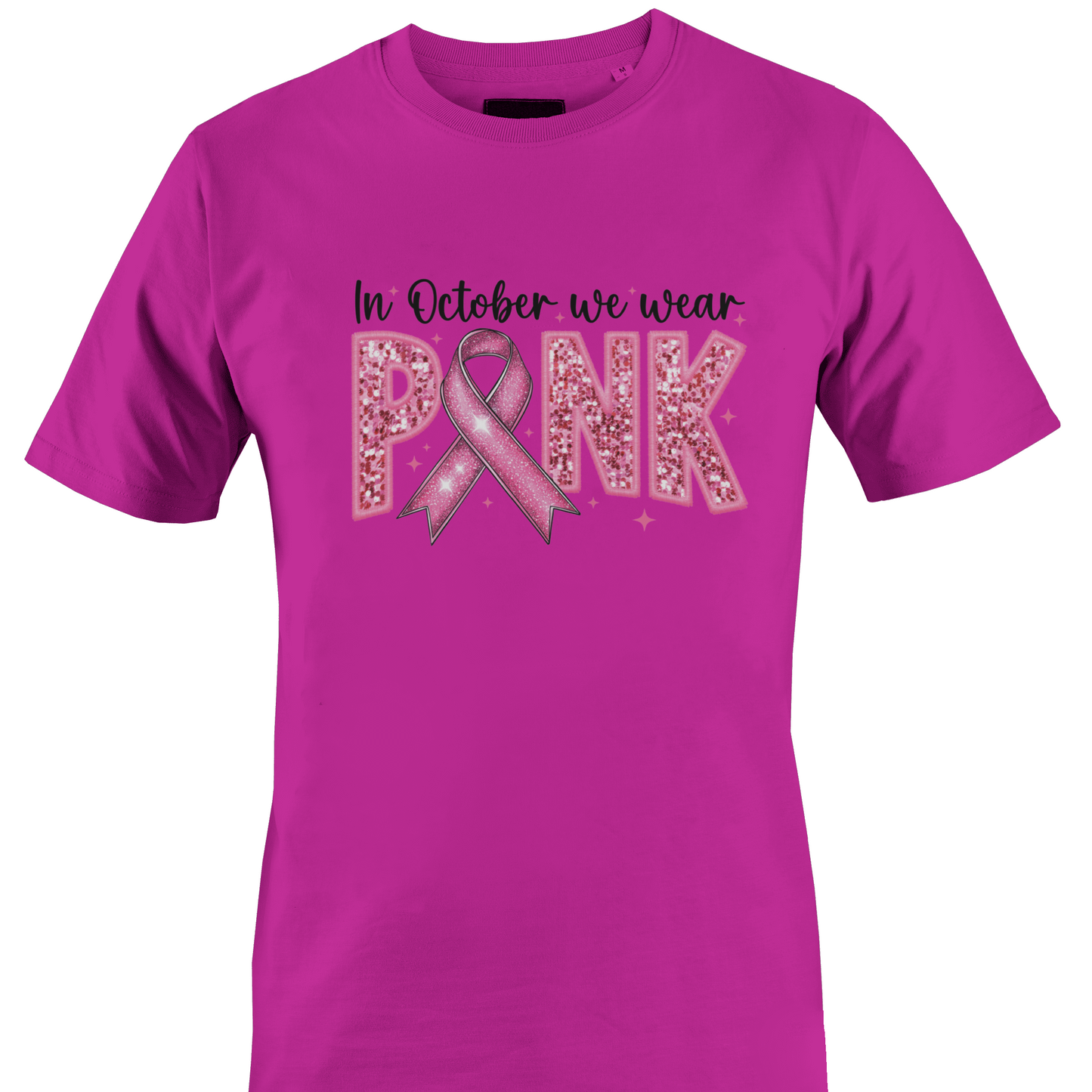 A bright pink short-sleeve crewneck t-shirt featuring a pink graphic on the front that reads 'In October we wear PINK' with a pink ribbon and glitter-textured letters by Monkey's Creations. 