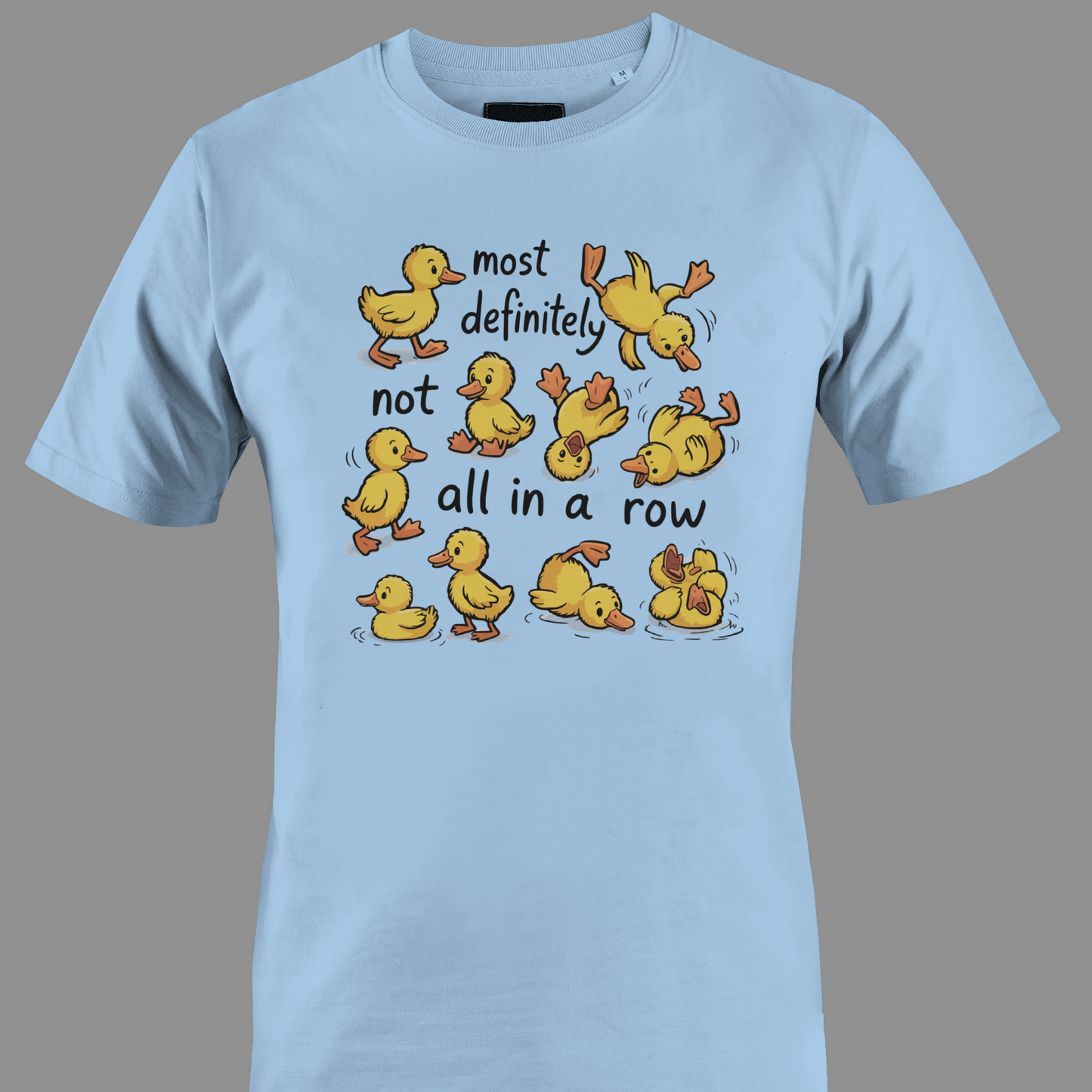 Light blue t-shirt with yellow ducklings and text most definitely not all in a row