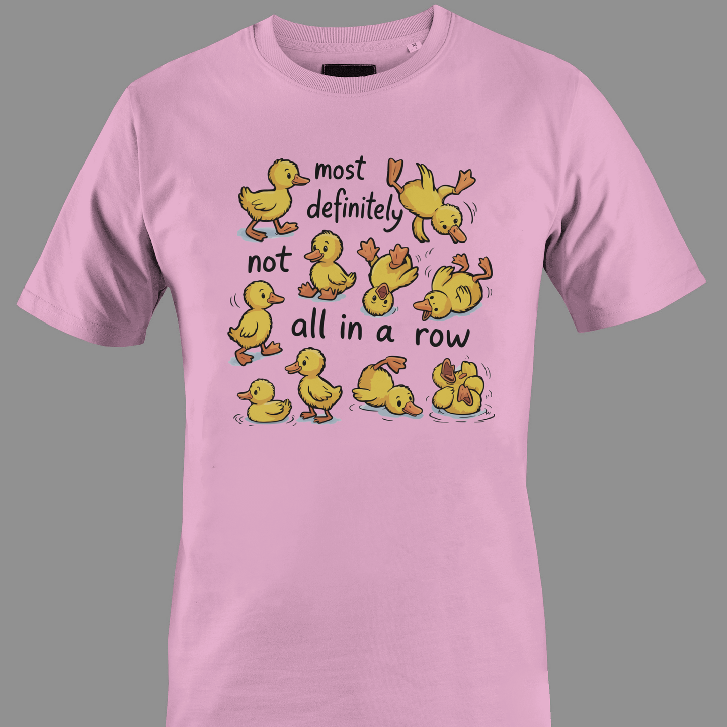 Light pink t-shirt with yellow ducklings and text most definitely not all in a row