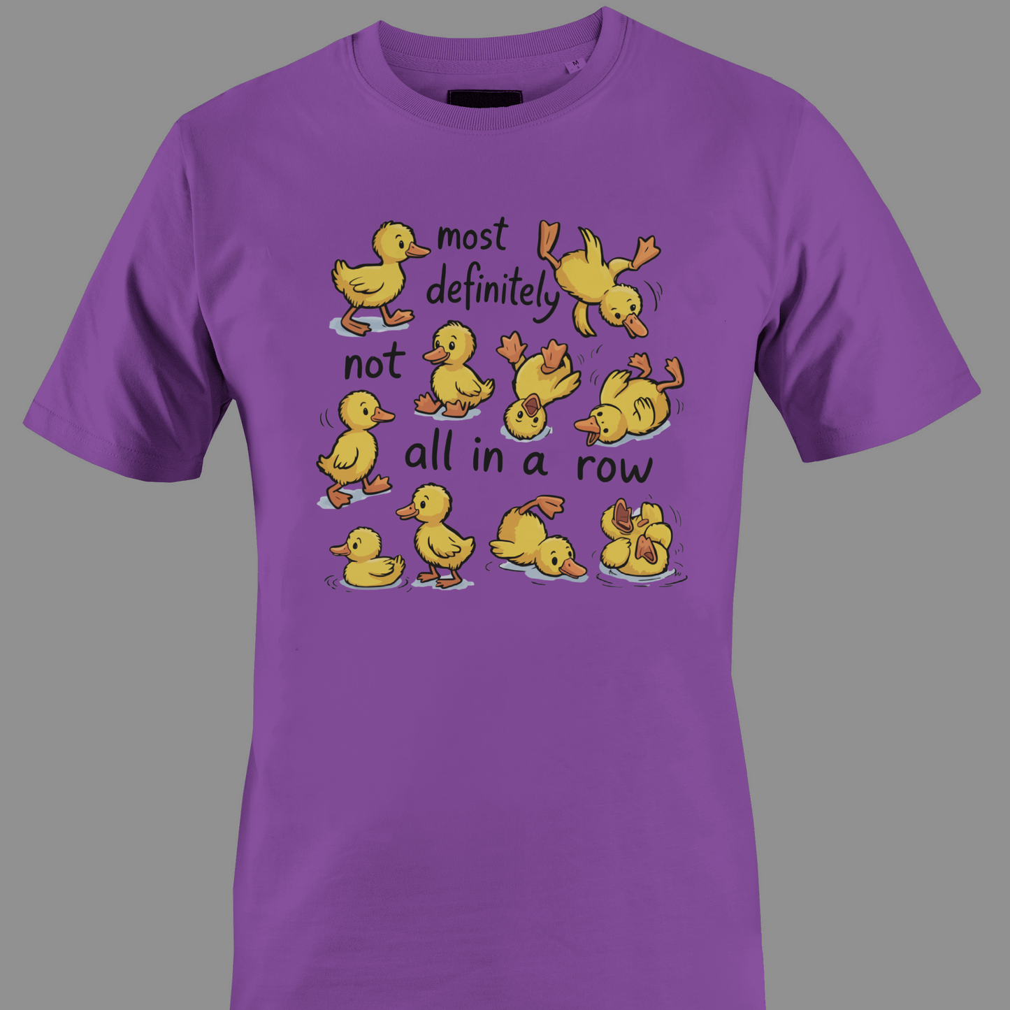 Purple t-shirt with yellow ducklings and text most definitely not all in a row