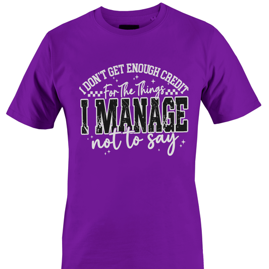 A dark purple short-sleeve crewneck t-shirt with a humorous graphic printed on the chest. The text reads 'I DON'T GET ENOUGH CREDIT For The Things I MANAGE not to say' in white and black distressed lettering with small star accents by Monkey's Creations.