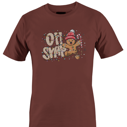 A brown short-sleeve crewneck t-shirt featuring a festive graphic on the chest with the text 'OH SNAP' in a patterned font, a gingerbread man wearing a red knit hat and holding a candy cane, and small snowflake details by Monkey's Creations.