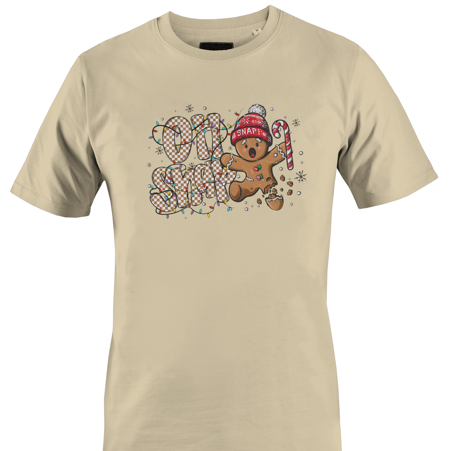 A tan short-sleeve crewneck t-shirt featuring a festive graphic on the chest with the text 'OH SNAP' in a patterned font, a gingerbread man wearing a red knit hat and holding a candy cane, and small snowflake details by Monkey's Creations.