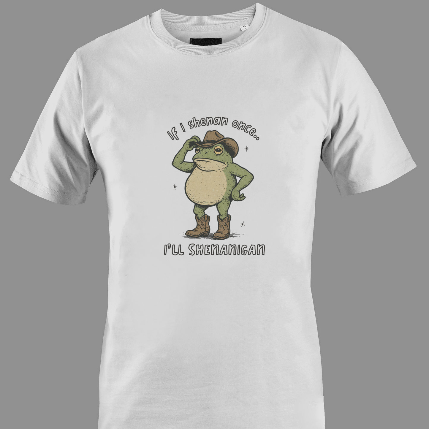 White t-shirt with a graphic of a frog wearing a cowboy hat and text saying shenan once, shenanigan