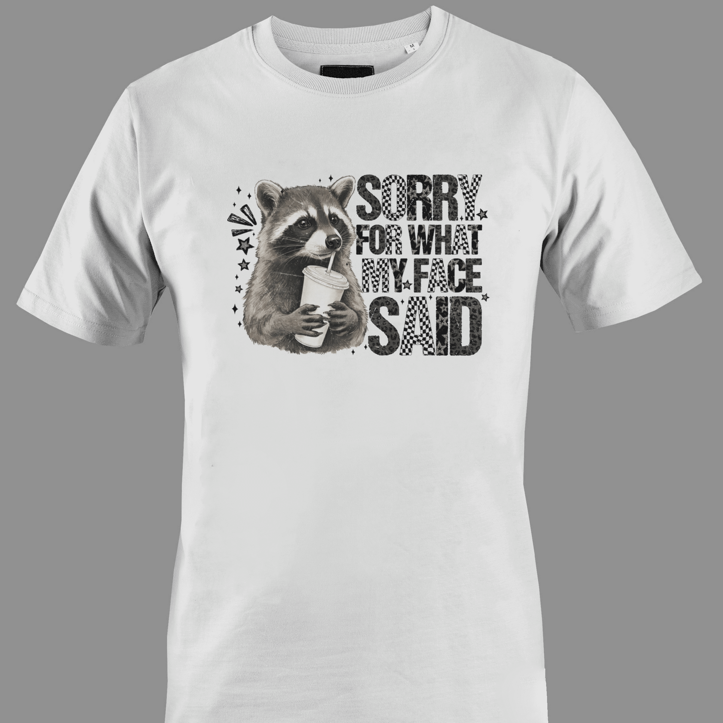 White t-shirt with a raccoon graphic and text sorry for what  my face said