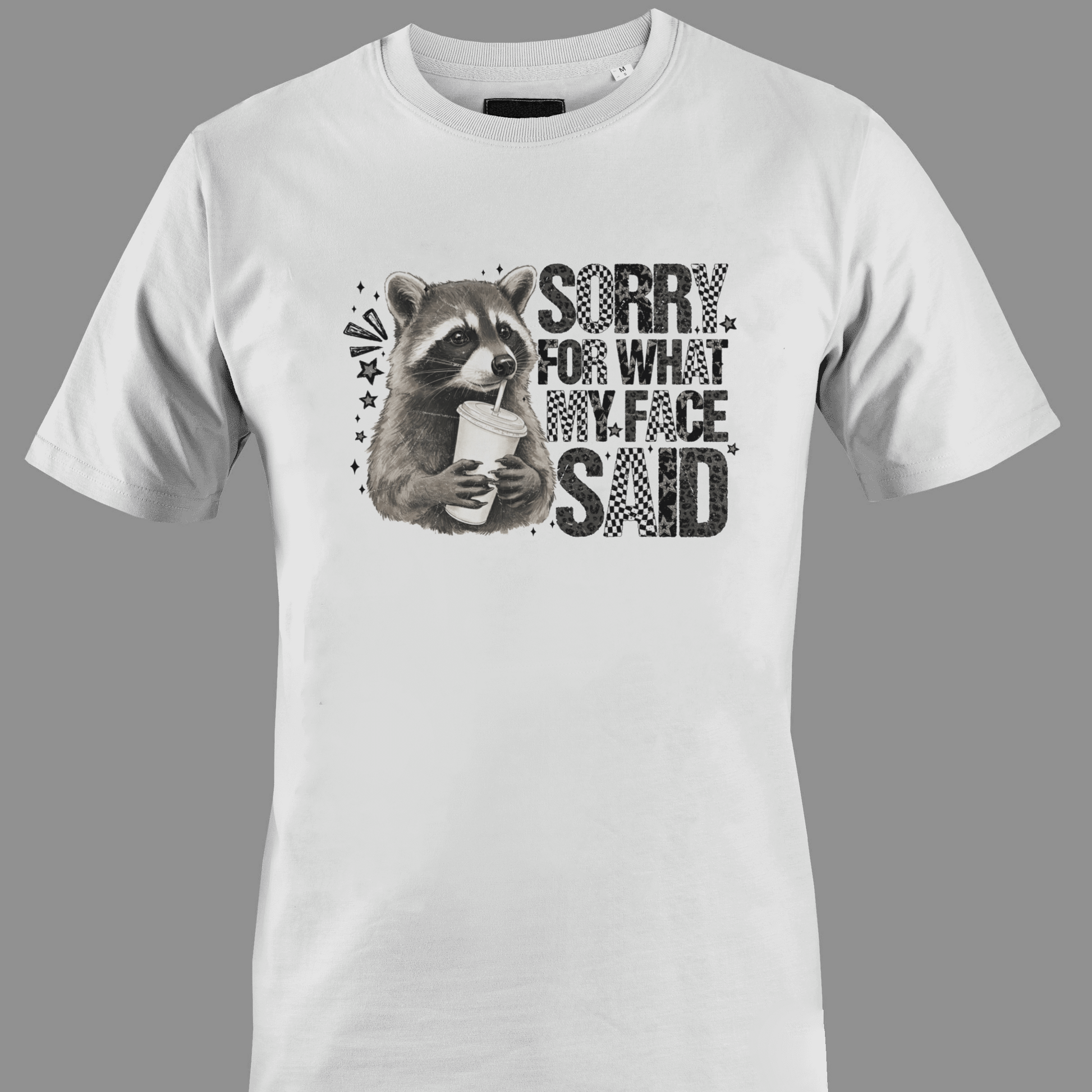 White t-shirt with a raccoon graphic and text sorry for what  my face said