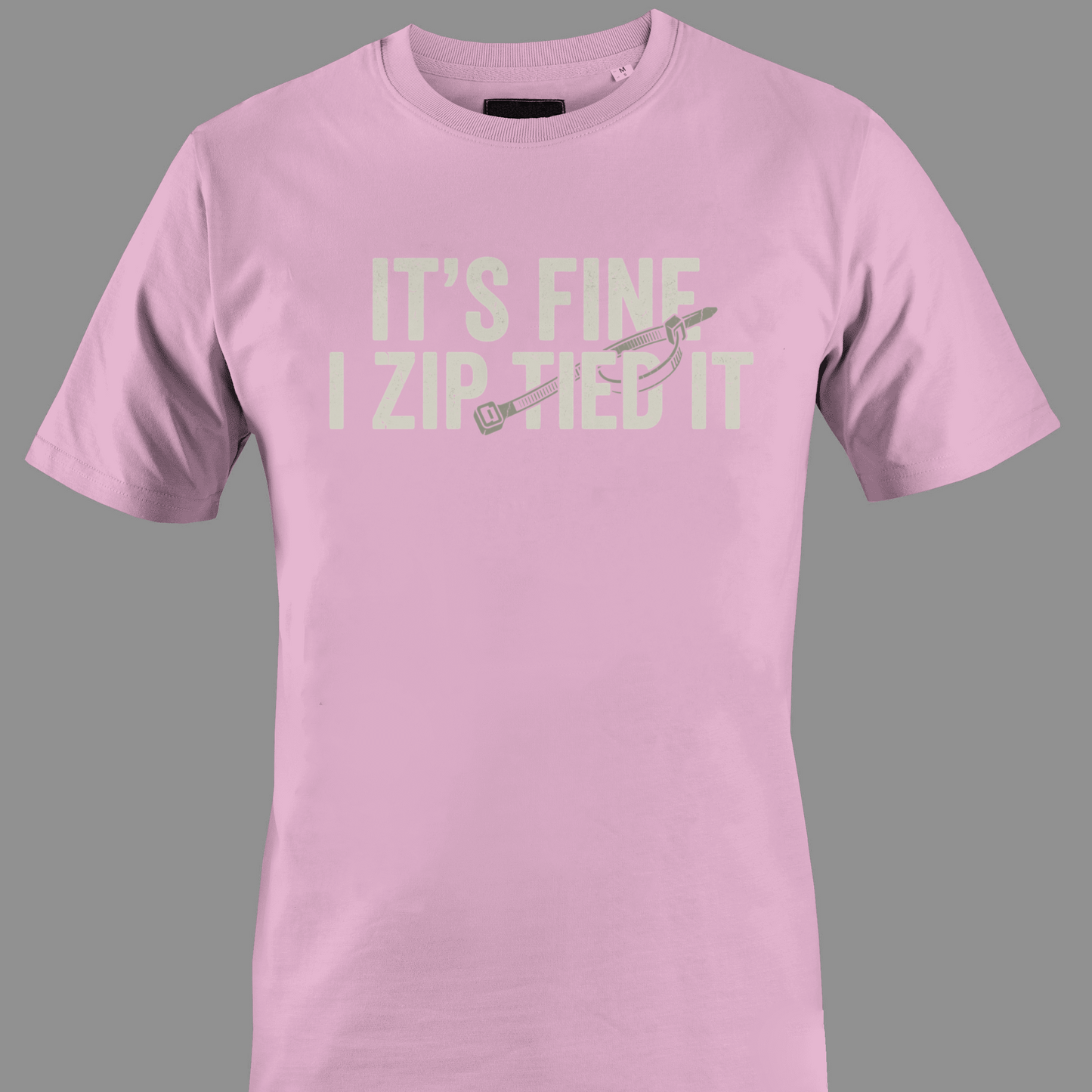 Light pink t-shirt with white text 'IT'S FINE I ZIP TIED IT' 