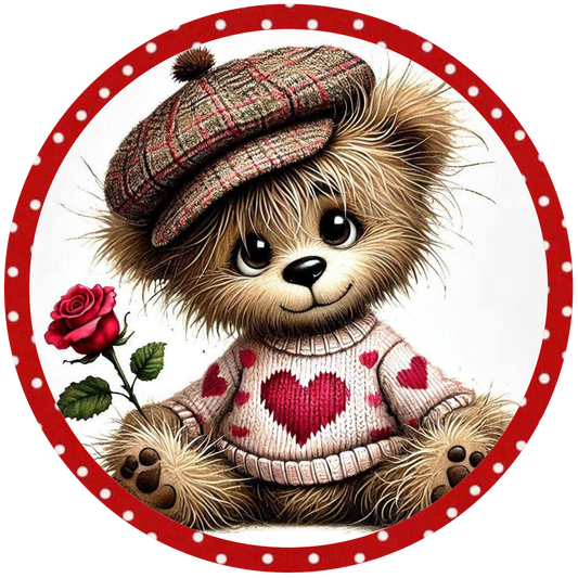Round metal wreath sign with a teddy bear with a plaid hat and heart sweater holding a rose 