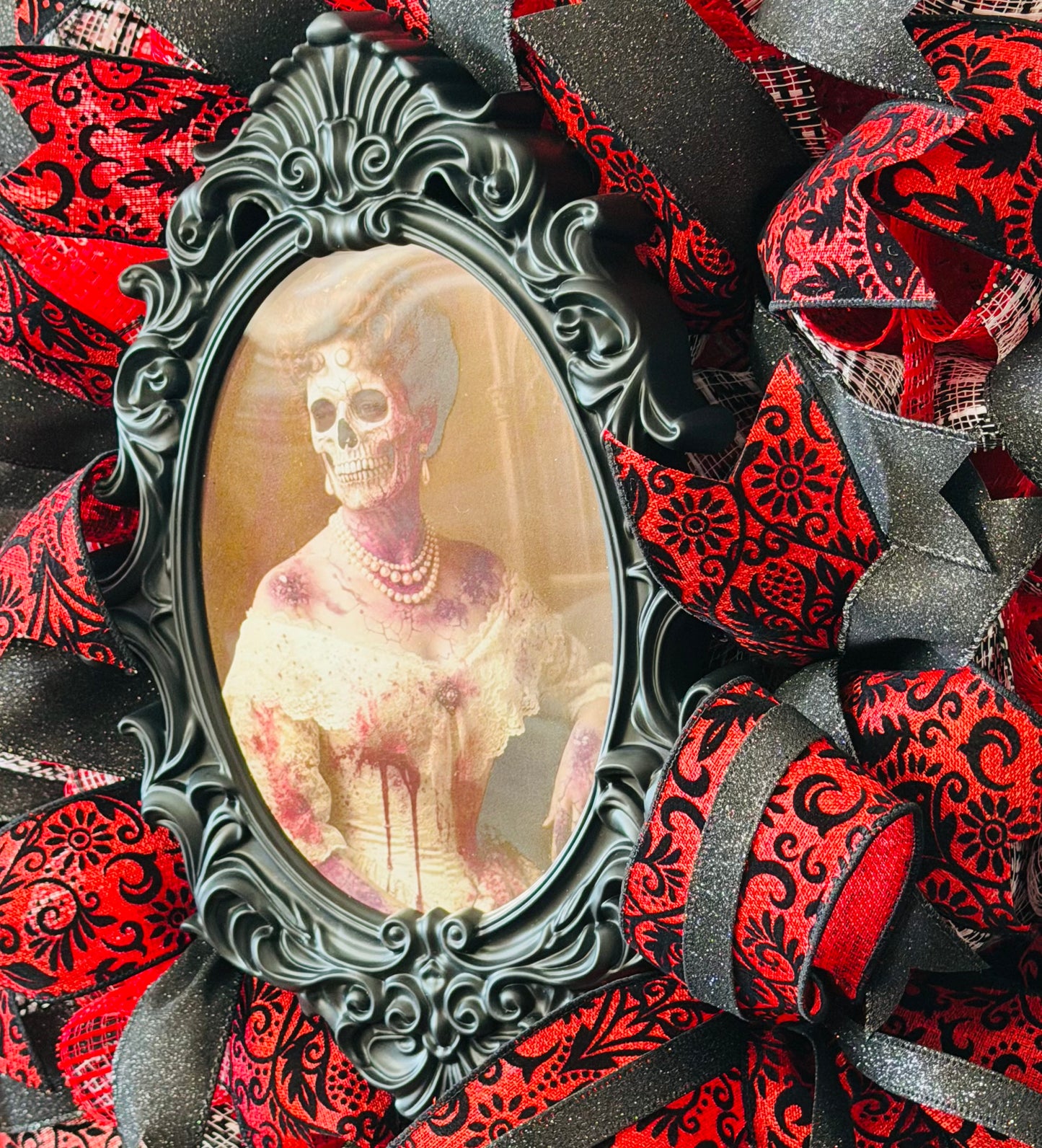 Round red and black vintage damask inspired deco mesh and ribbon wreath with with a photo of a lady / skeleton in the middle that changes to a creepy skeleton when the viewing angle is changed by Monkey's Creations.