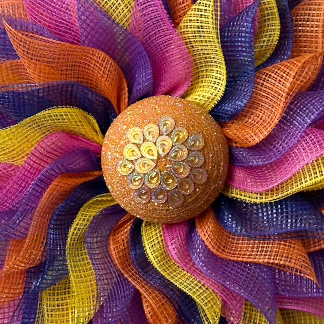 Deco mesh flower wreath with multicolored petals and an orange gemstone flower center 