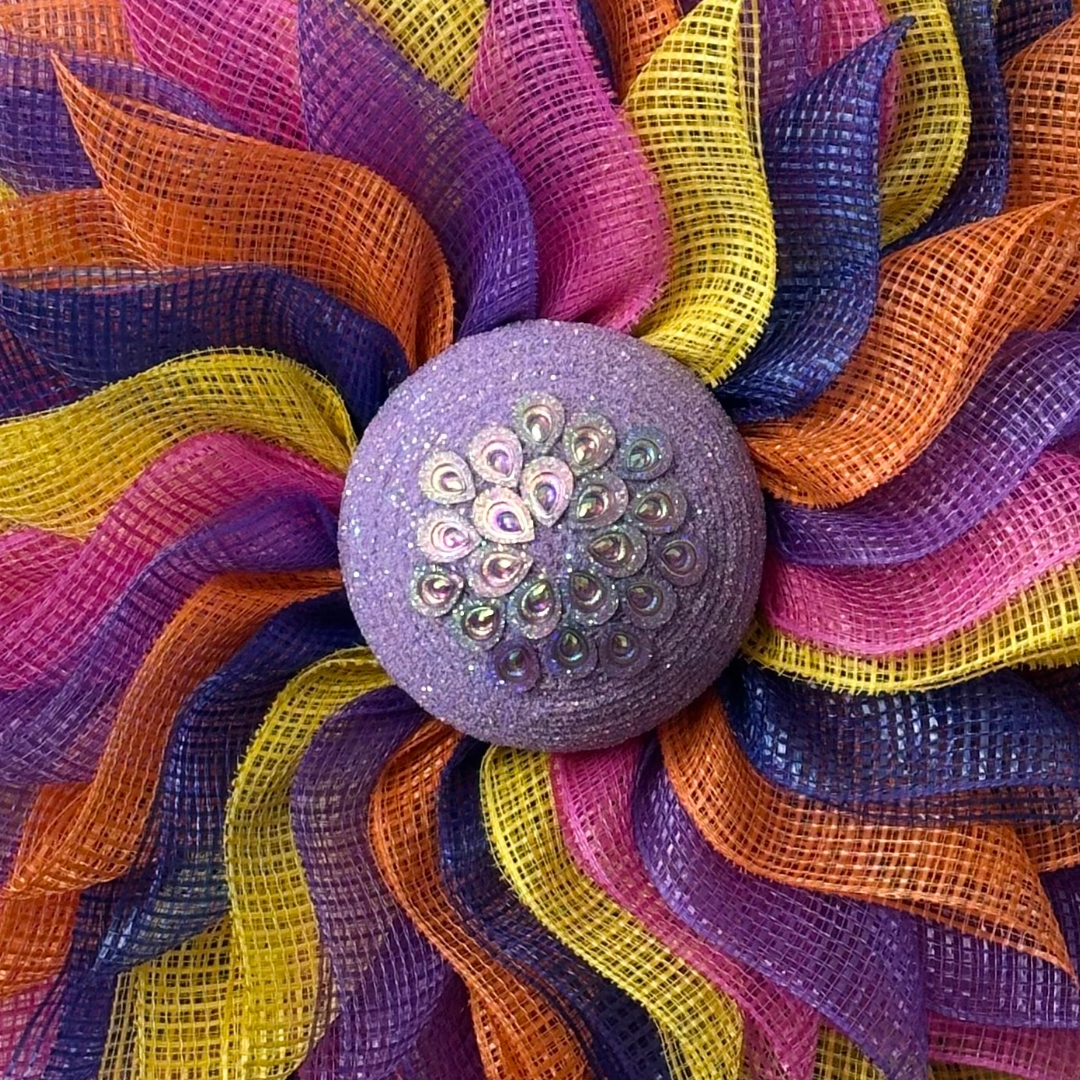 Deco mesh flower wreath with multicolored petals and an purple gemstone flower center 