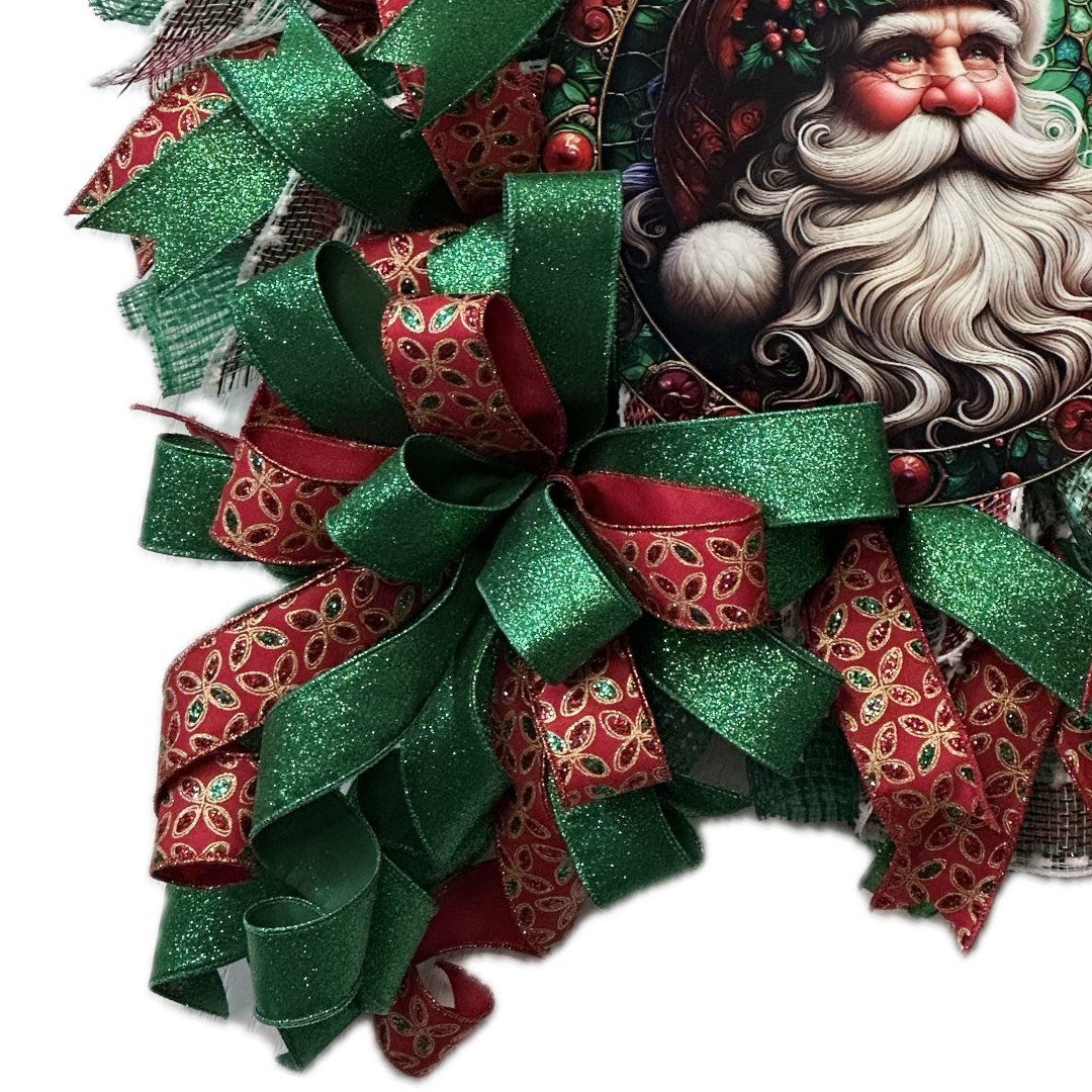 A red green and gold deco mesh and ribbon Christmas wreath with a vintage Santa Claus metal wreath sign center by Monkey's Creations.