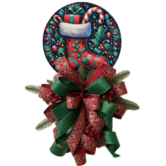 A festive Christmas wreath decoration featuring a red stocking metal wreath sign with candy canes, holly and berries, accented with a large red and green bow, faux glitter berries and faux pine branches by Monkey's Creations. 