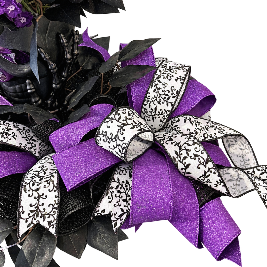 Black and purple themed Halloween skull centerpiece featuring floral picks, purple, black and white ribbon and black focus picks by Monkey's Creations. 