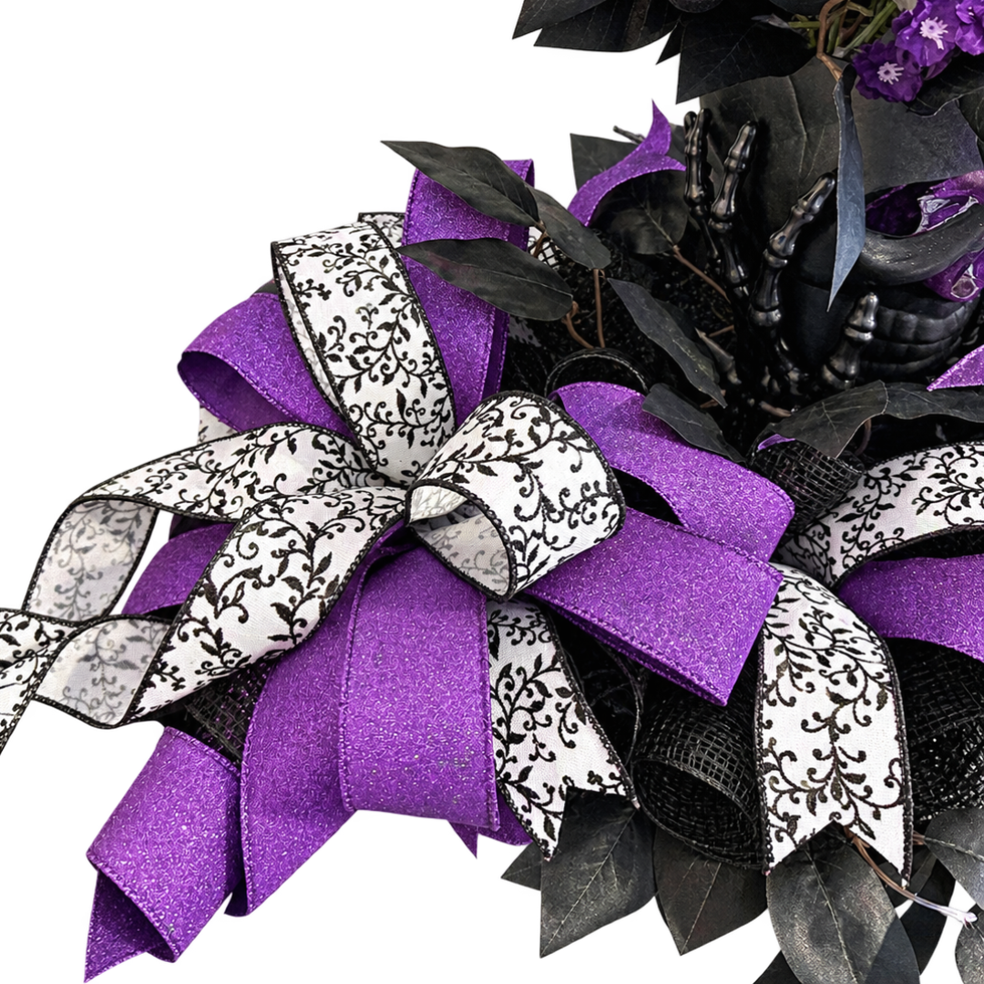 Black and purple themed Halloween skull centerpiece featuring floral picks, purple, black and white ribbon and black focus picks by Monkey's Creations. 