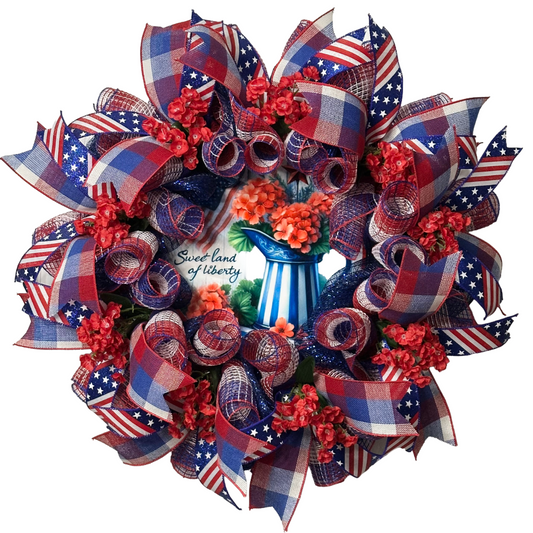 Deco mesh and ribbon wreath with red, white, and blue ribbons and flowers, featuring a 'Sweet Land of Liberty' by Monkey's Creations.