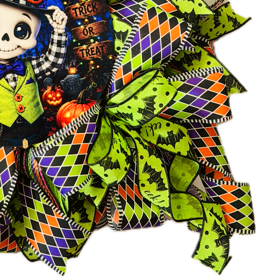 Orange, purple, black and lime green Halloween deco mesh and ribbon wreath featuring a round dapper skeleton with "trick or treat" metal wreath sign and a large ribbon bow by Monkey's Creations. 