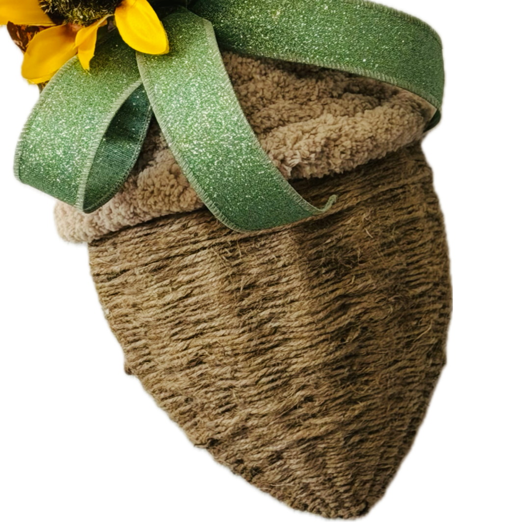 A chunky yarn and twine acorn door hanger or wreath attachment embellished with fall foliage, sunflowers and sage glitter wire ribbon by Monkey's Creations. 