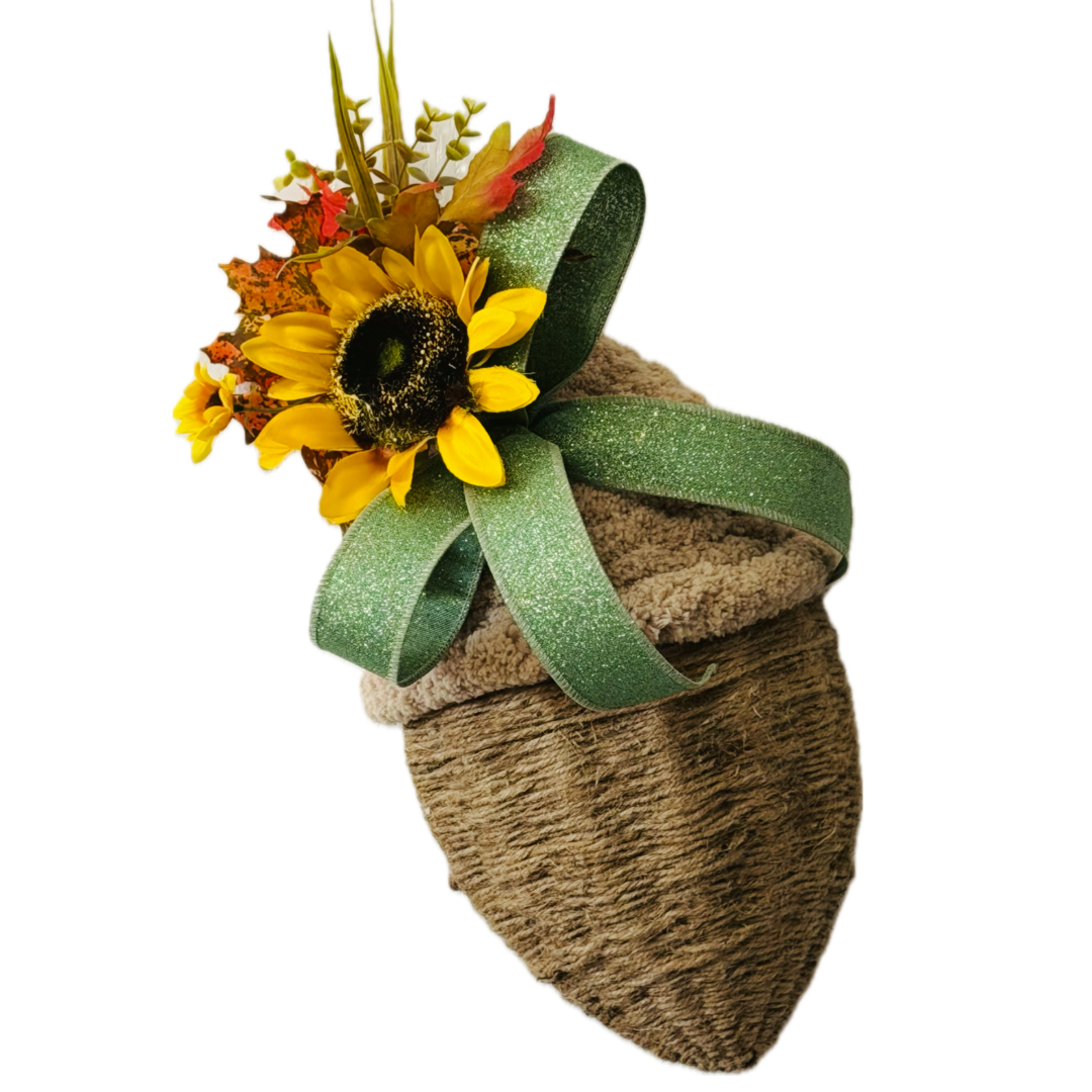 A chunky yarn and twine acorn door hanger or wreath attachment embellished with fall foliage, sunflowers and sage glitter wire ribbon by Monkey's Creations. 