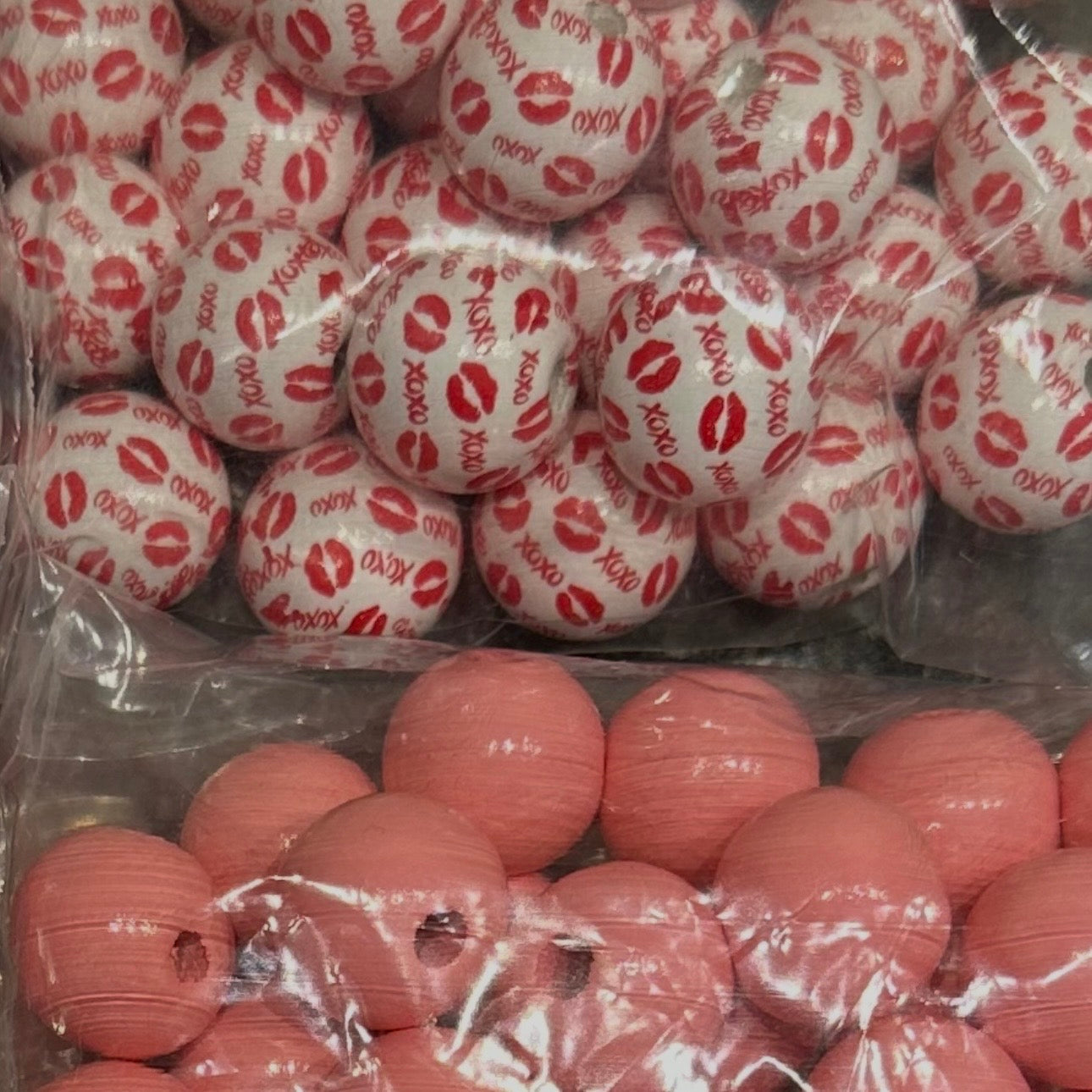 close up of pink wooden beads and white beads with red lips and xoxo 