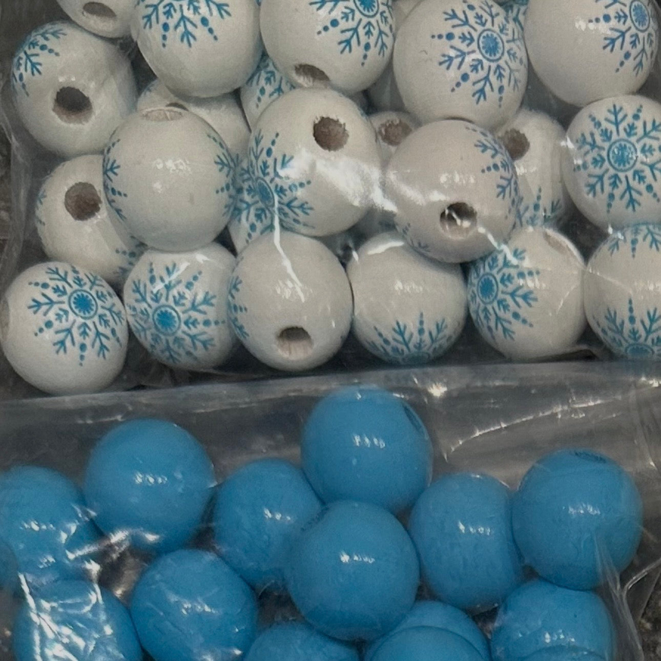 close up of blue wooden beads and white wooden beads with snowflakes