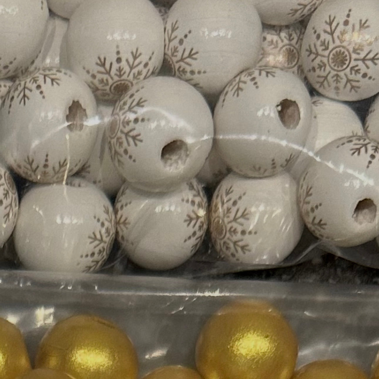 close up of gold and white wooden beads with a snowflake design